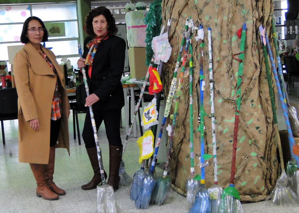 Photo of Bibliotecóloga y profesora del Colegio público Bilbao IED en Bogotá con las escobas hechas a partir de material reutilizable